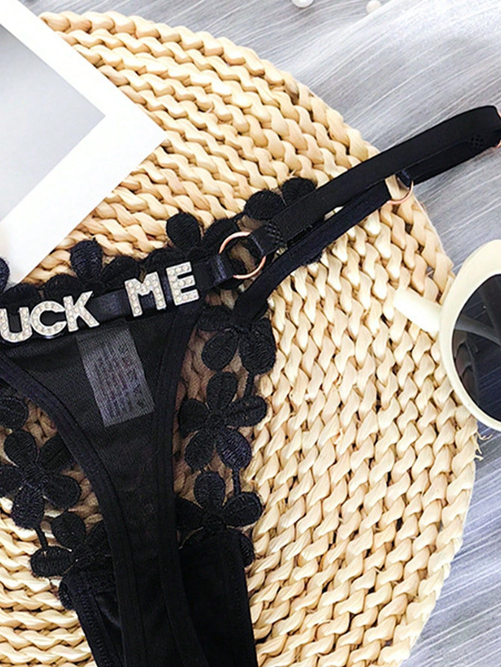 Close-up of personalized rhinestone letter details on black floral lace thong